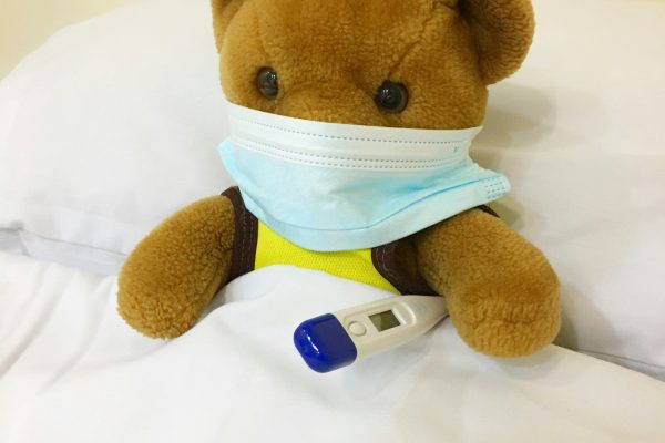 Teddy Bear with mask and thermometer in Bed
