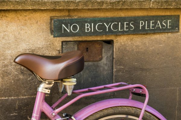 photo of a bicycle parked in front of a "no bicycles please" sign