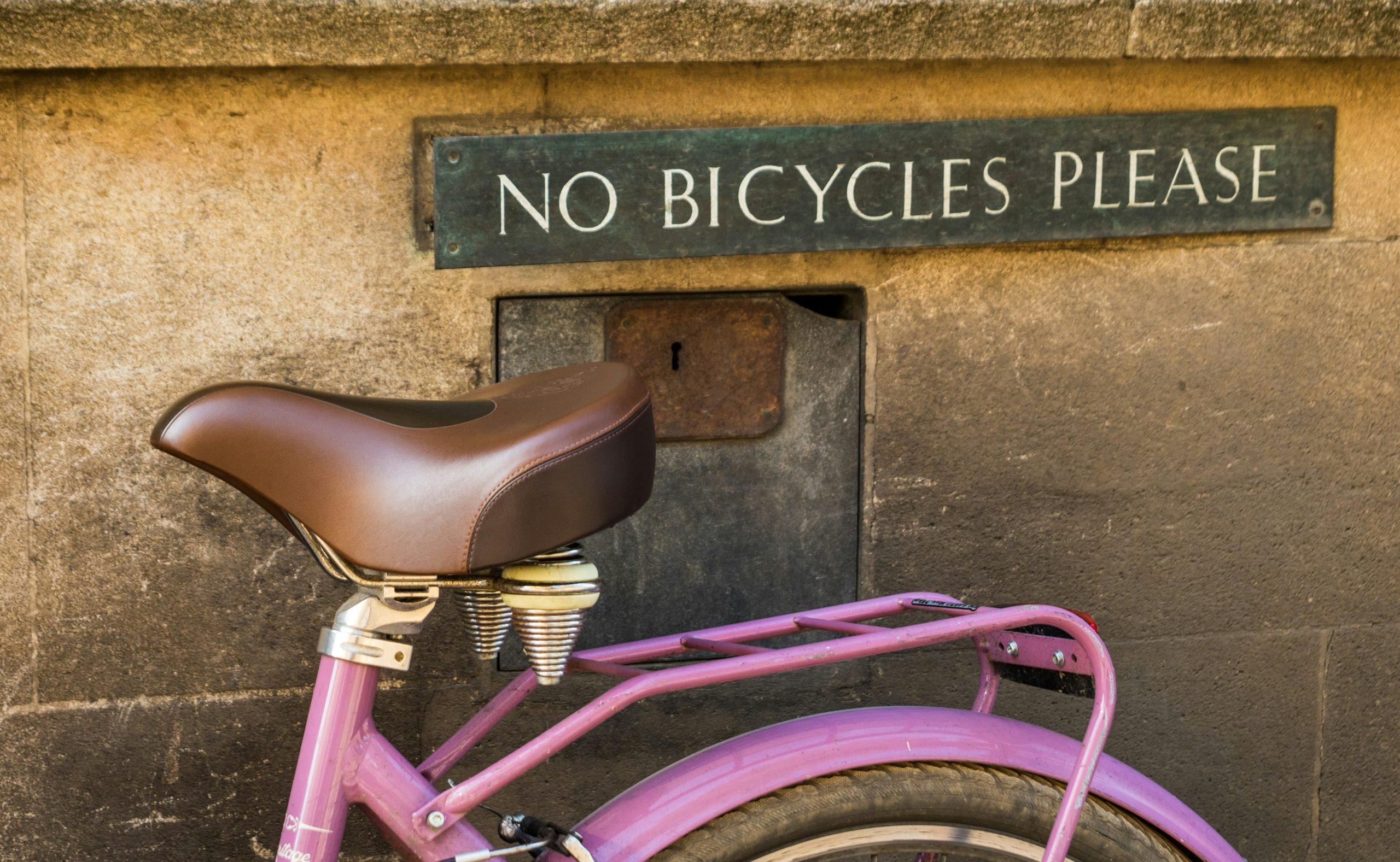 photo of a bicycle parked in front of a "no bicycles please" sign